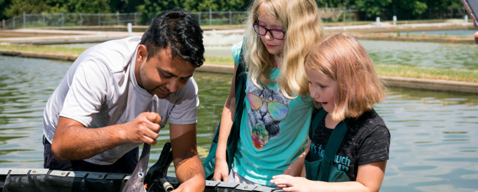 Aquaculture-Systems-adult male and two children inspecting a fish