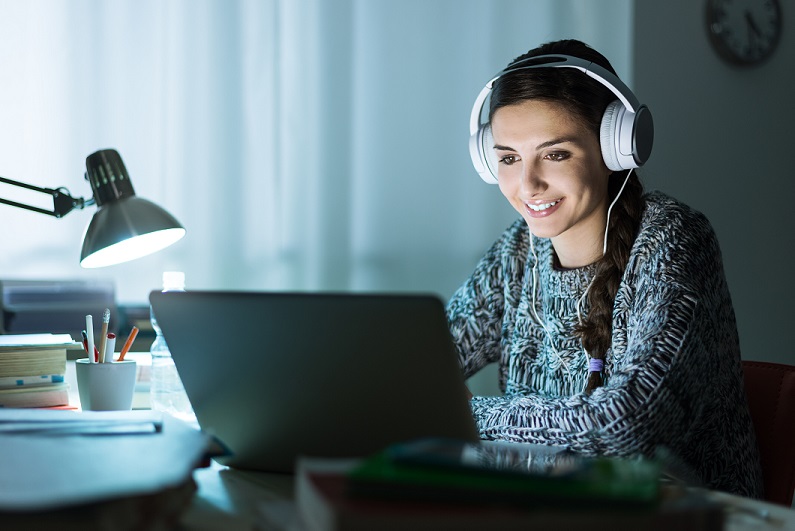 White female sudent sitting at a desk in front of a computer screen iStock photo