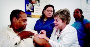 DNP giving a patient a shot with two nurses in the background